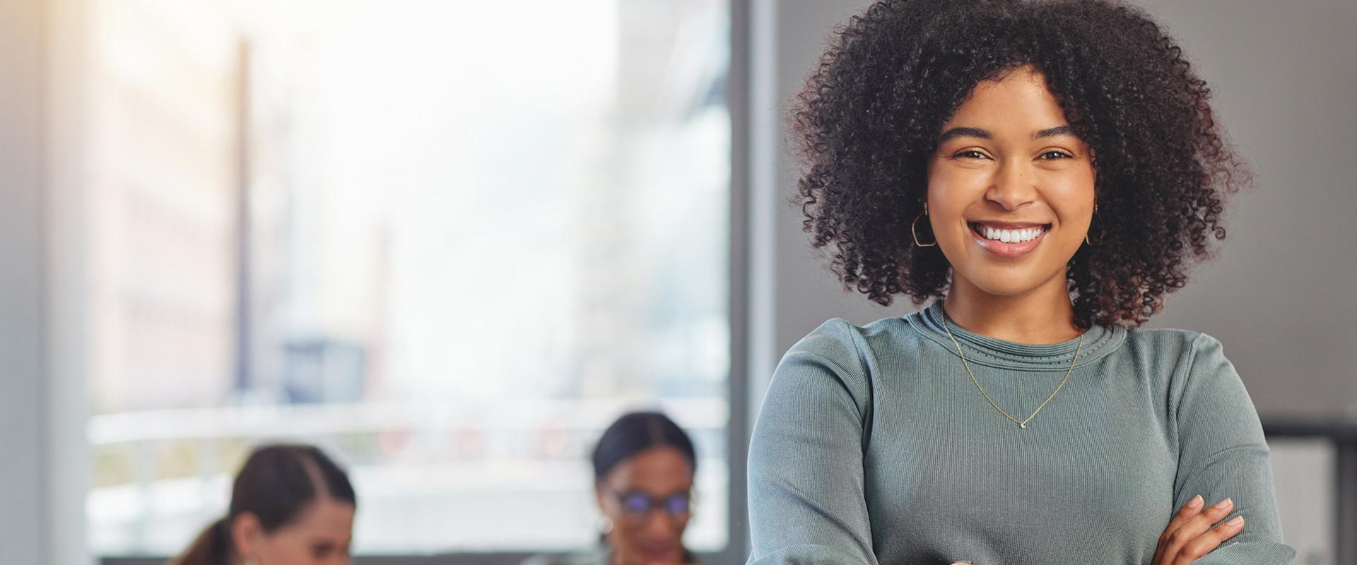 Femme souriante qui regarde devant, équipe de travail à l'arrière-plan