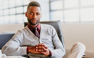 Jeune homme africain confiant assis les mains jointes