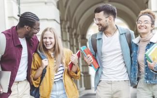 Groupe de quatre jeunes souriants qui sont aux études