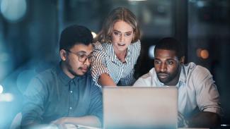 Jeunes gens d'affaires travaillant ensemble sur un portable, tard le soir