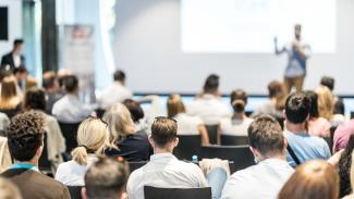 Des gens qui assistent à une conférence dans un auditorium devant un professeur