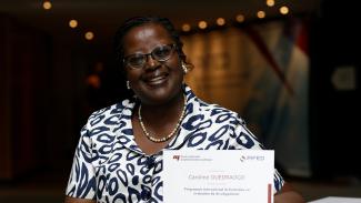 Femme tenant fièrement son diplôme du Programme international de formation en évaluation du développement (PIFED)