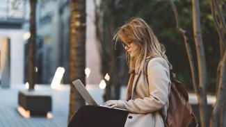 Femme utilisant un ordinateur portable sur un banc dehors