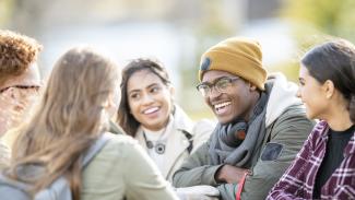 Étudiantes et étudiants d'ethnicité mixte souriants en discussion à l'extérieur.