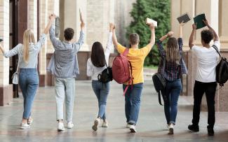 Groupe d'étudiantes et d'étudiants vue de dos les bras dans les airs illustrant la réussite