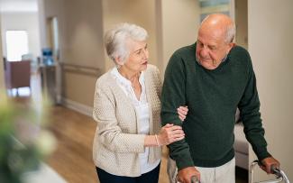 Femme âgée aidant son mari à marcher à l'aide d'un déambulateur dans une maison de retraite