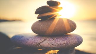 Des pierres en équilibre avec rayons de soleil pour illustrer la santé mentale saine