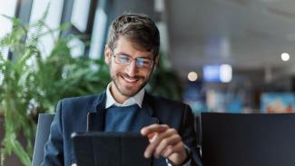 Homme souriant utilisant une tablette numérique.